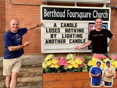 Twin brothers with sign stating "A Candle Loses Nothing by Lighting Another Candle"